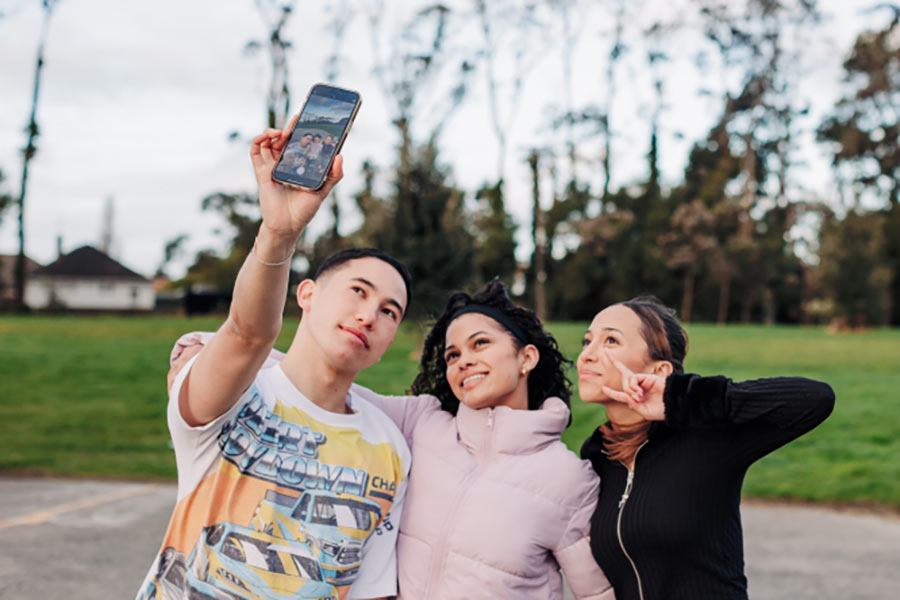 Photo of three young people taking a selfie outdoors